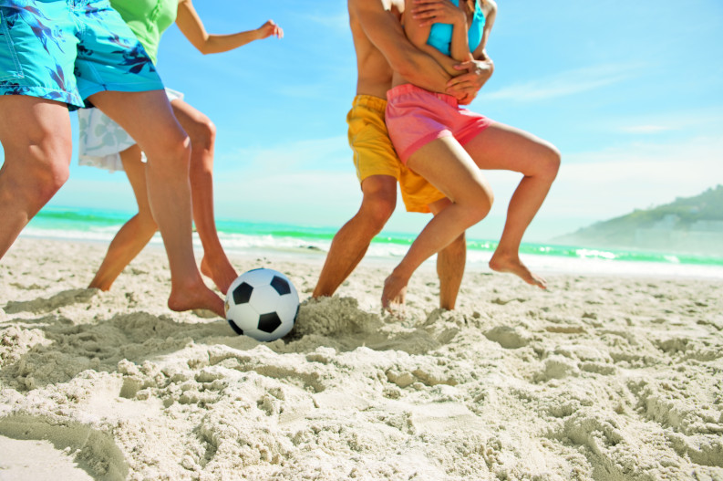 Kinder spielen Fußball am Strand